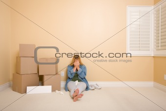 Upset Woman with Tissues on Floor Next to Boxes and Blank Sign in Empty Room.