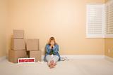 Upset Woman with Tissues on Floor Next to Boxes and Foreclosure Real Estate Sign in Empty Room.