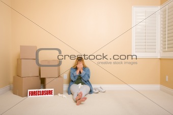 Upset Woman with Tissues on Floor Next to Boxes and Foreclosure Real Estate Sign in Empty Room.