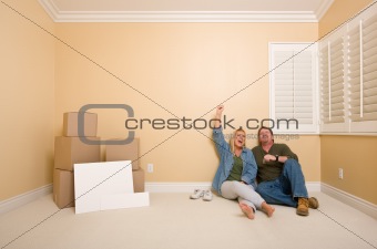 Excited Couple Relaxing on Floor Near Boxes and Blank Real Estate Signs in Empty Room