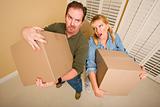 Obviously Exhausted Couple Holding Moving Boxes in Empty Room.