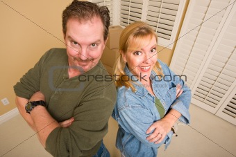 Smiling Goofy Couple and Moving Boxes in Empty Room.