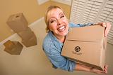 Excited Woman Holding Moving Boxes in Empty Room Taken with Extreme Wide Angle Lens.
