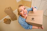Excited Woman with Thumbs Up and Moving Boxes in Empty Room Taken with Extreme Wide Angle Lens.
