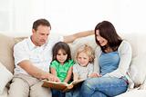 Cheerful family looking at a photo album together on the sofa