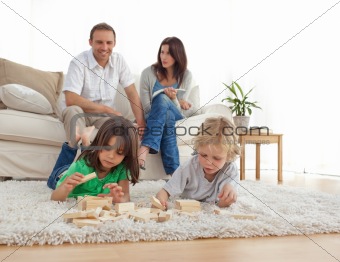 Happy parents on the sofa looking at their children playing on t