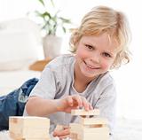 Happy boy playing with dominoes lying on the floor
