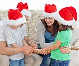 Family opening crackers together on the sofa