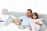 Handsome man with lying on his bed with his children at waking 