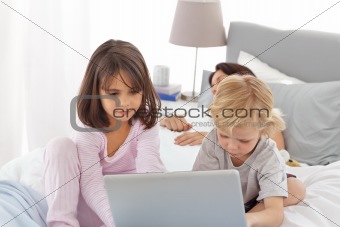Cute brother and sister on internet while their mother is sleepi