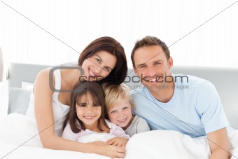 Portrait of a happy family sitting on the bed 