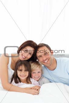 Portrait of a joyful family sitting on the bed