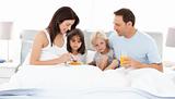 Lovely family having breakfast on the bed