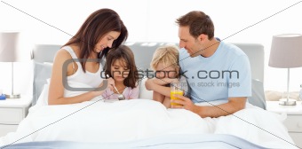 Adorable children having breakfast on the bed with their parents