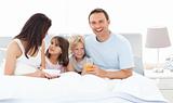 Happy family having breakfast together on the bed