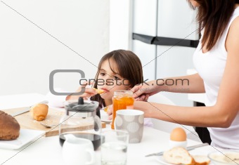 Pretty mother giving toast with jam to her daughter for the bread
