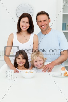 Happy parents posing with their children in the kitchen