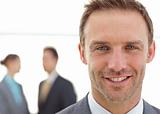 Cheerful businessman posing in front of his team while working