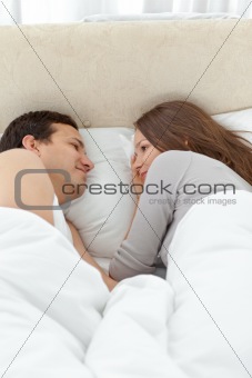 Cute couple looking at each other while relaxing on the bed