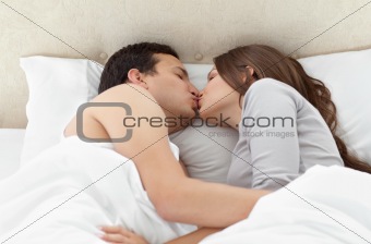 Lovely couple kissing in each other's arms on the bed 