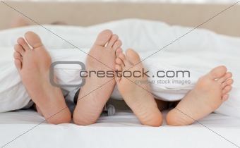 Close up of couple's feet while relaxing in their bed