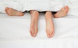 Close up of couple's feet while hugging in their bed