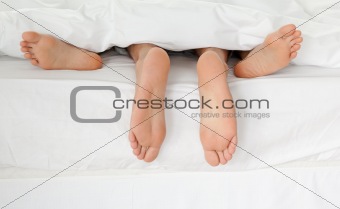 Close up of couple's feet while hugging in their bed