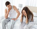 Worried man looking at his girlfriend having a headache on the bed