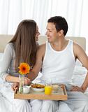 Passionate couple with their breakfast sitting on the bed