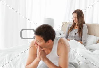 Woman working on the laptop while her boyfriend is worrying