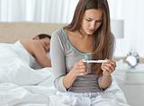 Pretty woman looking a pregnancy test while her boyfriend sleepi