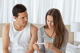 Worried couple looking at a pregnancy test sitting on their bed