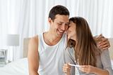 Cheerful couple with a pregnancy test in the bedroom