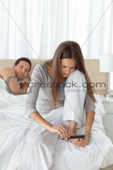 Man waiting for his girlfriend filing her toenails on the bed