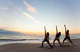 Three Women Practicing Yoga on Beach At Sunrise or Sunset