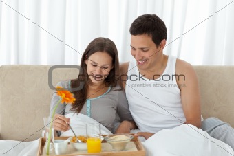Young woman having breakfast on the bed with her boyfriend 