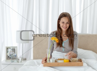 Portrait of a young woman having breakfast on the bed