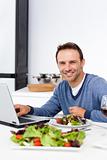 Cheerful man working on his laptop while having lunch