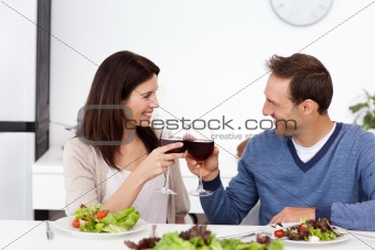 Lovely couple clinking glasses of red wine during lunch