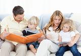 Family reading a book on their sofa