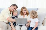 Adorable family working together on a laptop sitting on the sofa