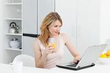 Woman drinking while she is looking at her laptop