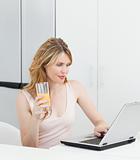 Woman drinking while she is looking at her laptop