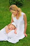 Young mother and daughter resting in meadow