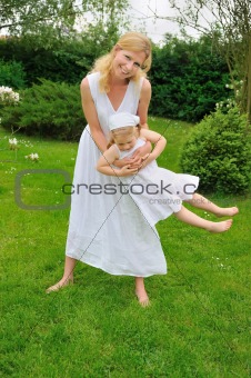 Young mother and daughter playing in meadow