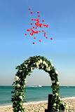 Beach wedding with red balloons and boat