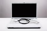 Stethoscope and white laptop