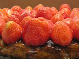 Lateral close-up view of a strawberry cake on brown background