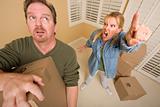 Stressed Man Moving Boxes for Demanding Wife Surrounded by Other Boxes.
