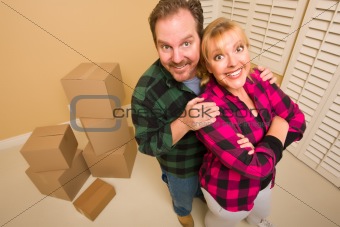 Proud Smiling Goofy Couple and Moving Boxes in Empty Room.